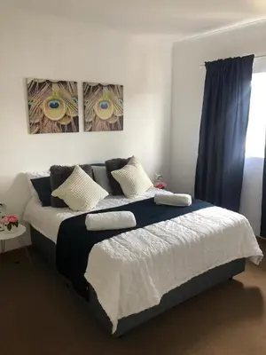 a bedroom with a large bed with blue curtains at Brackenfell self catering accommodation in Brackenfell
