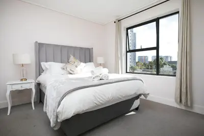 a white bedroom with a large bed with a window at 2 Bedroom Waters Edge Apartment in Century City in Cape Town