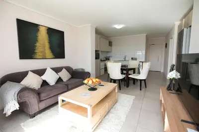 a living room with a couch and a table at 2 Bedroom Waters Edge Apartment in Century City in Cape Town