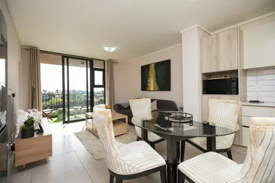 a living room with a glass table and chairs at 2 Bedroom Waters Edge Apartment in Century City in Cape Town