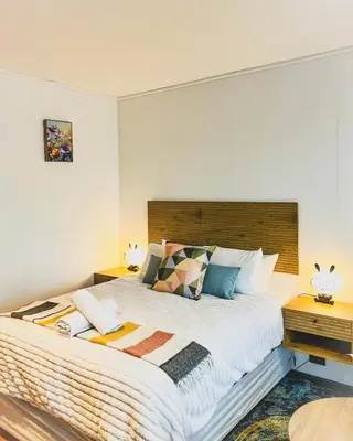 a bedroom with a large bed with a wooden headboard at Promise on Nine Palms Century in Cape Town