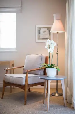 a living room with a chair and a table with a vase of flowers at Leeu House in Franschhoek