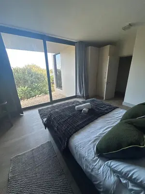 a bedroom with a large bed with a large window at Suite Vos in Hermanus