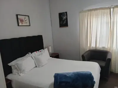 a hotel room with a bed and a chair at Lucian Bed and Breakfast in Goodwood