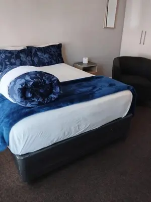 a bed with a blue blanket on it in a room at Lucian Bed and Breakfast in Goodwood