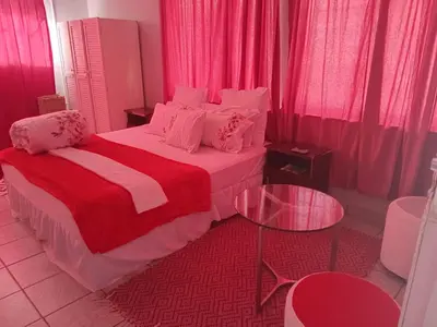 a bedroom with a bed with pink curtains and a table at Lucian Bed and Breakfast in Goodwood