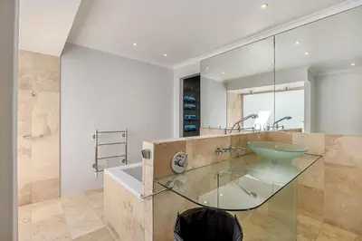 a bathroom with a glass sink and a tub at The Island Beach House in Cape Town
