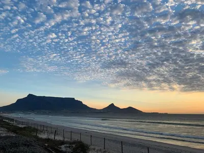 a view of a beach with a cloudy sky at The Island Beach House in Cape Town