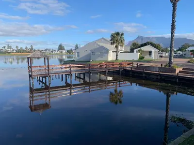 a dock in the water next to a house at The Island Beach House in Cape Town