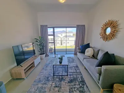 a living room with a couch and a flat screen tv at 118 on the Bay in Gordonʼs Bay