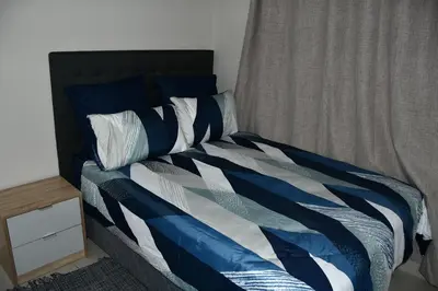 a bed with a blue and white comforter and pillows at Avon Sand in Cape Town