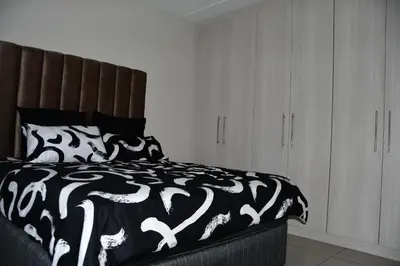 a bedroom with a bed with a black and white blanket at Avon Sand in Cape Town