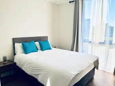a bedroom with a bed with blue pillows and a window at Modern chic at On park Century City near Canal Walk in Cape Town