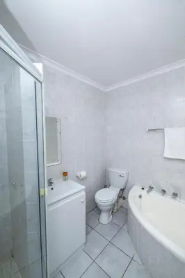 a bathroom with a toilet and a tub and a sink at Prime Executive Apartments 2 in Durbanville