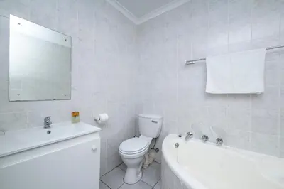 a white bathroom with a toilet and a bath tub at Prime Executive Apartments 2 in Durbanville