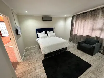 a small bedroom with a bed and a chair at Joy House in Cape Town