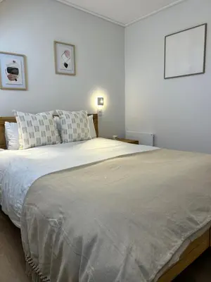 a large bed in a bedroom with two pictures on the wall at Central Town Duplex with Pool, BBQ & Mountain View in Hermanus