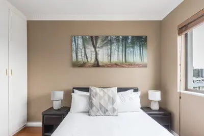 a bedroom with a white bed with two night stands at Modern City Apartment with Balcony & Braai in Cape Town