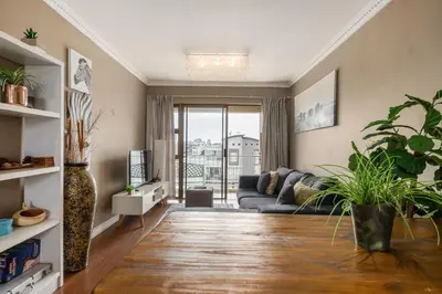 a living room with a couch and some plants at Modern City Apartment with Balcony & Braai in Cape Town