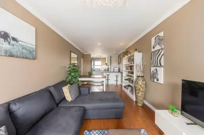 a living room with a couch and a tv at Modern City Apartment with Balcony & Braai in Cape Town