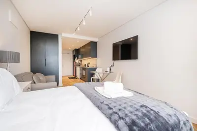 a bedroom with a white bed and a living room at Paarl Studio With Onsite Parking & Modern Comforts in Paarl