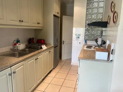 a kitchen with white cabinets and a sink at Golfers paradise on 25th green in Hermanus