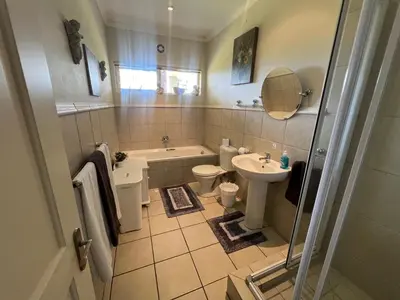 a bathroom with a tub toilet and a sink at Golfers paradise on 25th green in Hermanus