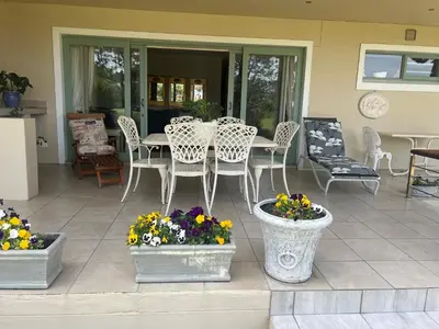 a patio with a table and chairs and flowers at Golfers paradise on 25th green in Hermanus