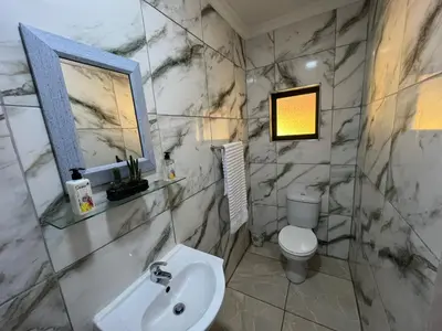a marble bathroom with a sink and a toilet at Minak Guest House Bellville in Bellville