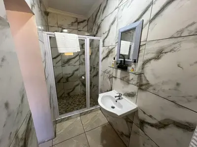 a white bathroom with a shower and a sink at Minak Guest House Bellville in Bellville