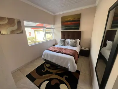 a small bedroom with a bed and a window at Minak Guest House Bellville in Bellville