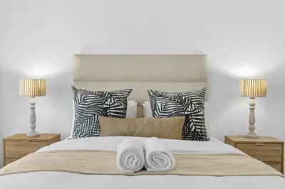a bedroom with a white bed with two lamps at Panoramic Seaview @ Strand in Strand