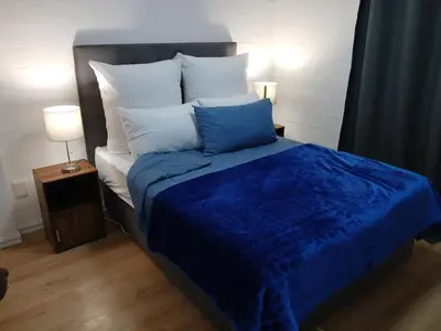 a bed with a blue comforter and white pillows at Fisherman's Haven in Bloubergstrand