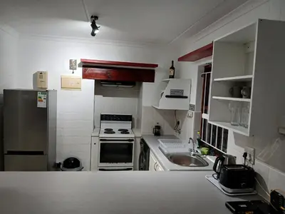 a small kitchen with a stove and a sink at Fisherman's Haven in Bloubergstrand
