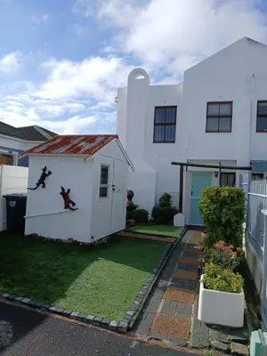 a white house with a dog on the side of it at Fisherman's Haven in Bloubergstrand