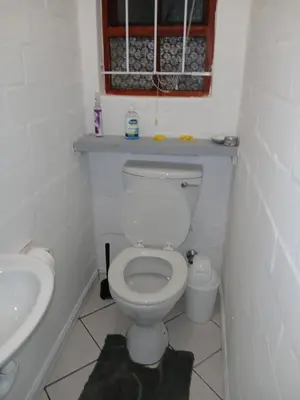 a small bathroom with a toilet and a sink at Fisherman's Haven in Bloubergstrand