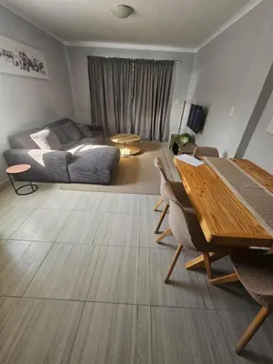 a living room with a table and a couch at 180 Mont Blanc in Gordonʼs Bay