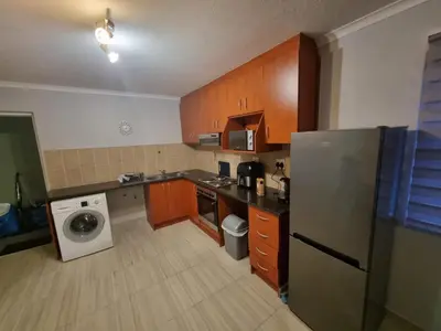 a kitchen with wooden cabinets and a washer and dryer at 180 Mont Blanc in Gordonʼs Bay