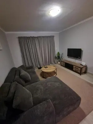 a living room with a couch and a flat screen tv at 180 Mont Blanc in Gordonʼs Bay