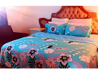 a bed with a blue comforter with flowers on it at Peace Accommodation B&B in Silver Sands