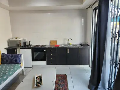 a small kitchen with a sink and a stove at G's Apartments Cape Town in Windsor Park