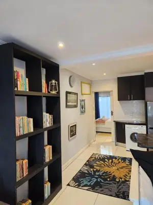 a living room with black book shelves and a rug at G's Apartments Cape Town in Windsor Park