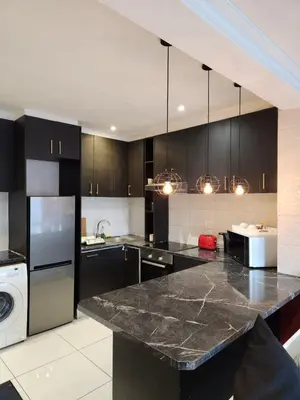 a kitchen with black cabinets and a black counter top at G's Apartments Cape Town in Windsor Park