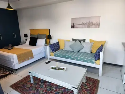a living room with two beds and a couch at G's Apartments Cape Town in Windsor Park