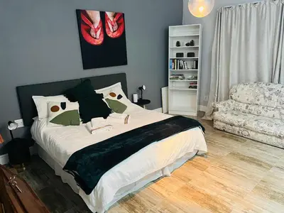 a bedroom with a large bed and a chair at Spacious Bachelor Die Boord in Stellenbosch