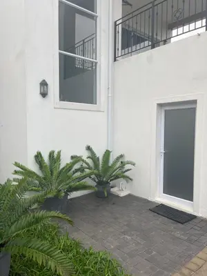 a building with two palm trees in front of a door at Spacious Bachelor Die Boord in Stellenbosch