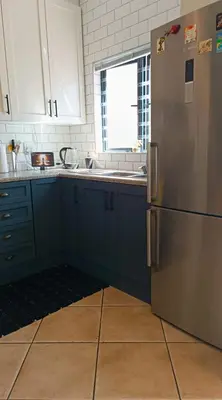 a kitchen with blue cabinets and a stainless steel refrigerator at Entire 2 Level Townhouse in Backenfell Cape Town in Brackenfell