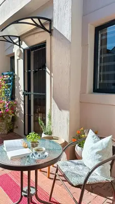 a patio with a table and chairs and a window at Entire 2 Level Townhouse in Backenfell Cape Town in Brackenfell