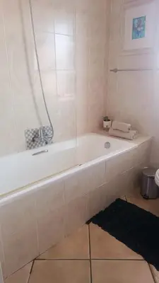 a white bath tub in a bathroom with a black rug at Entire 2 Level Townhouse in Backenfell Cape Town in Brackenfell