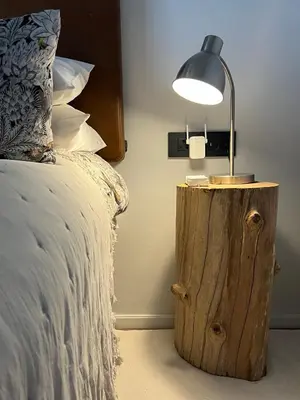 a lamp on a wooden stump next to a bed at Villa Victoria in Paarl